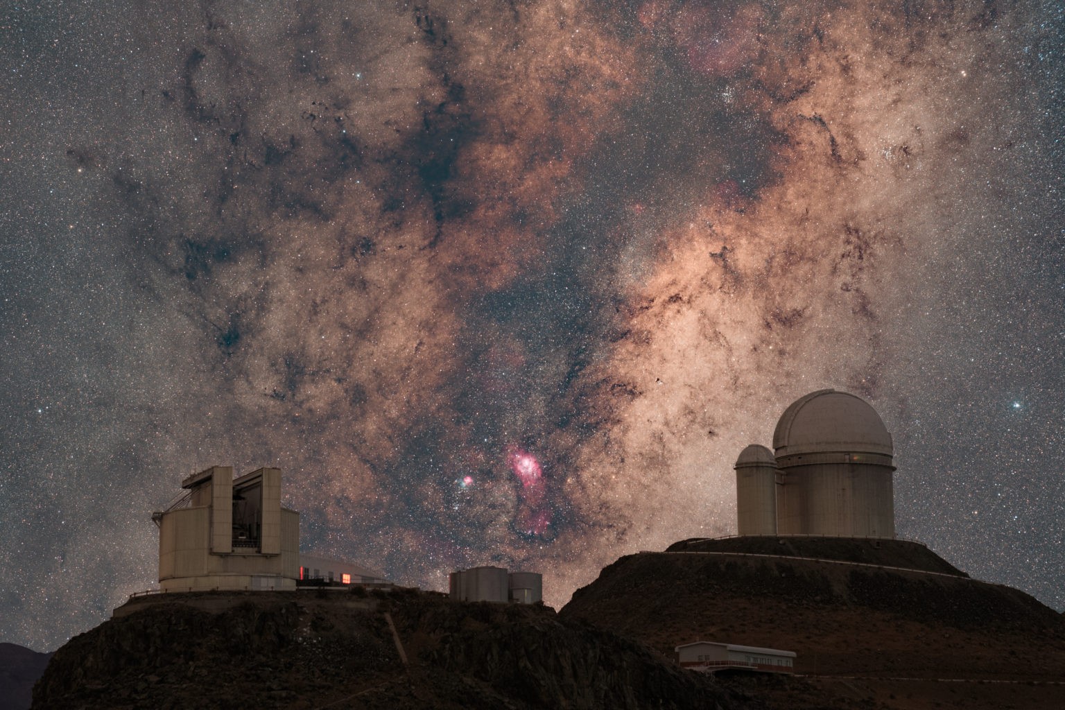 Picture of the Milky Way core rising behind the domes of the two 4m-class telescopes (NTT on the left and the famous exoplanet hunter the 3.6-meter) in La Silla